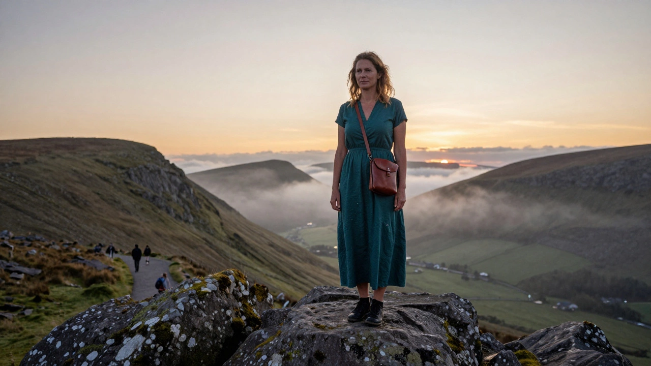 A woman at sunset on Croagh Patrick mountain wearing a damp but dry teal dress, surrounded by mist.