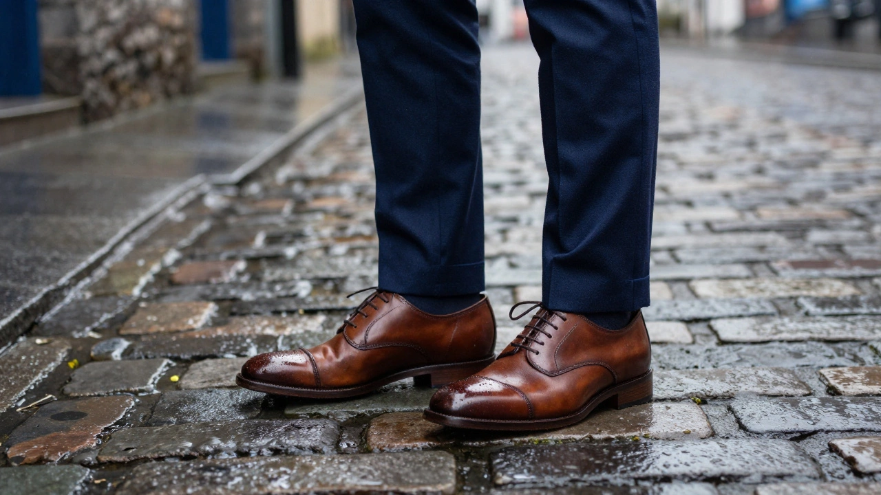 Brown leather shoes and blue suit hem on wet cobblestones